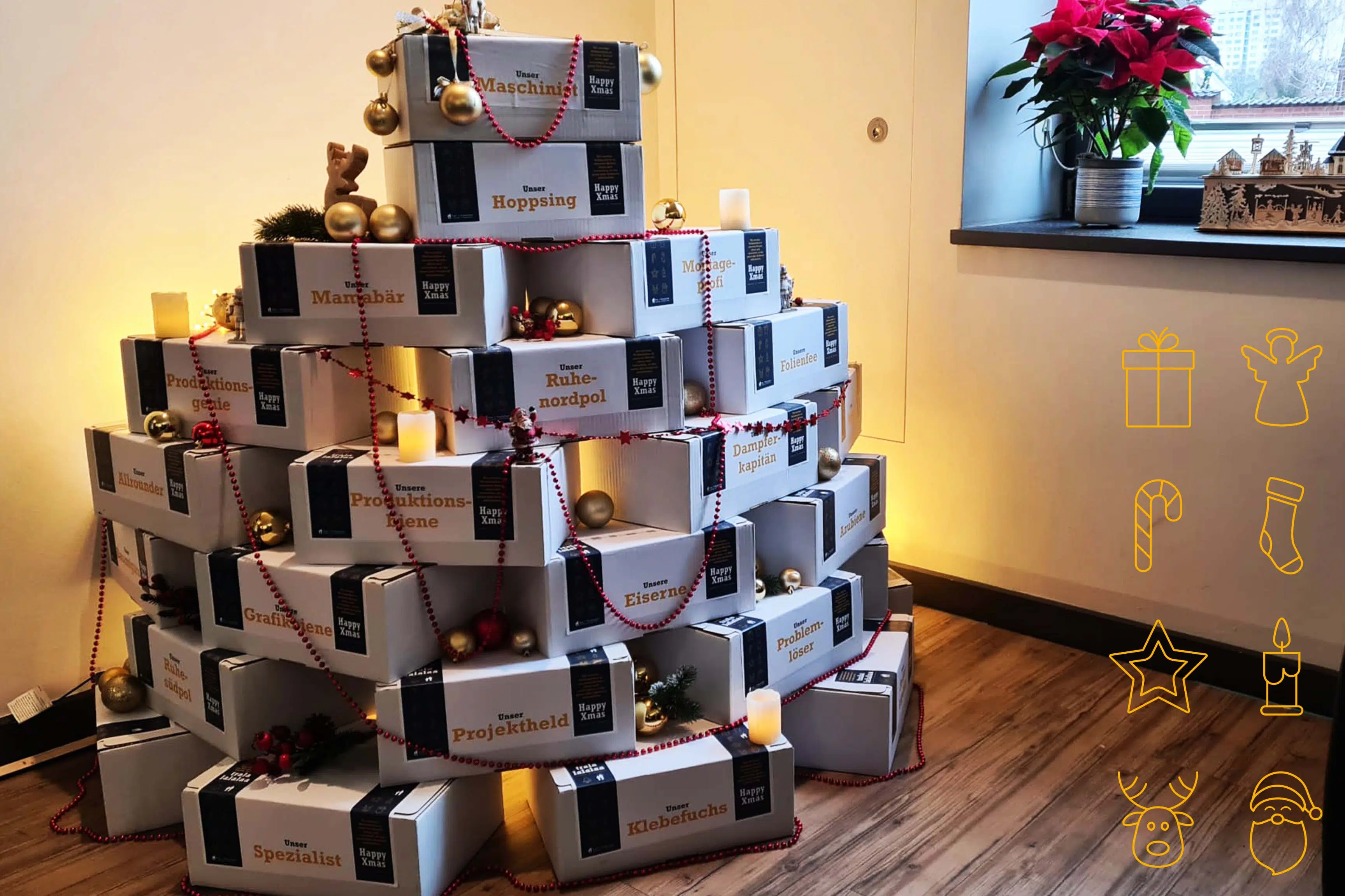 Ein festlich gestalteter Weihnachtsbaum aus gestapelten Geschenkboxen, liebevoll dekoriert mit Kugeln, Lichterketten und personalisierten Aufschriften. Eine kreative und einzigartige Art, Wertschätzung für das Team in der Weihnachtszeit auszudrücken.