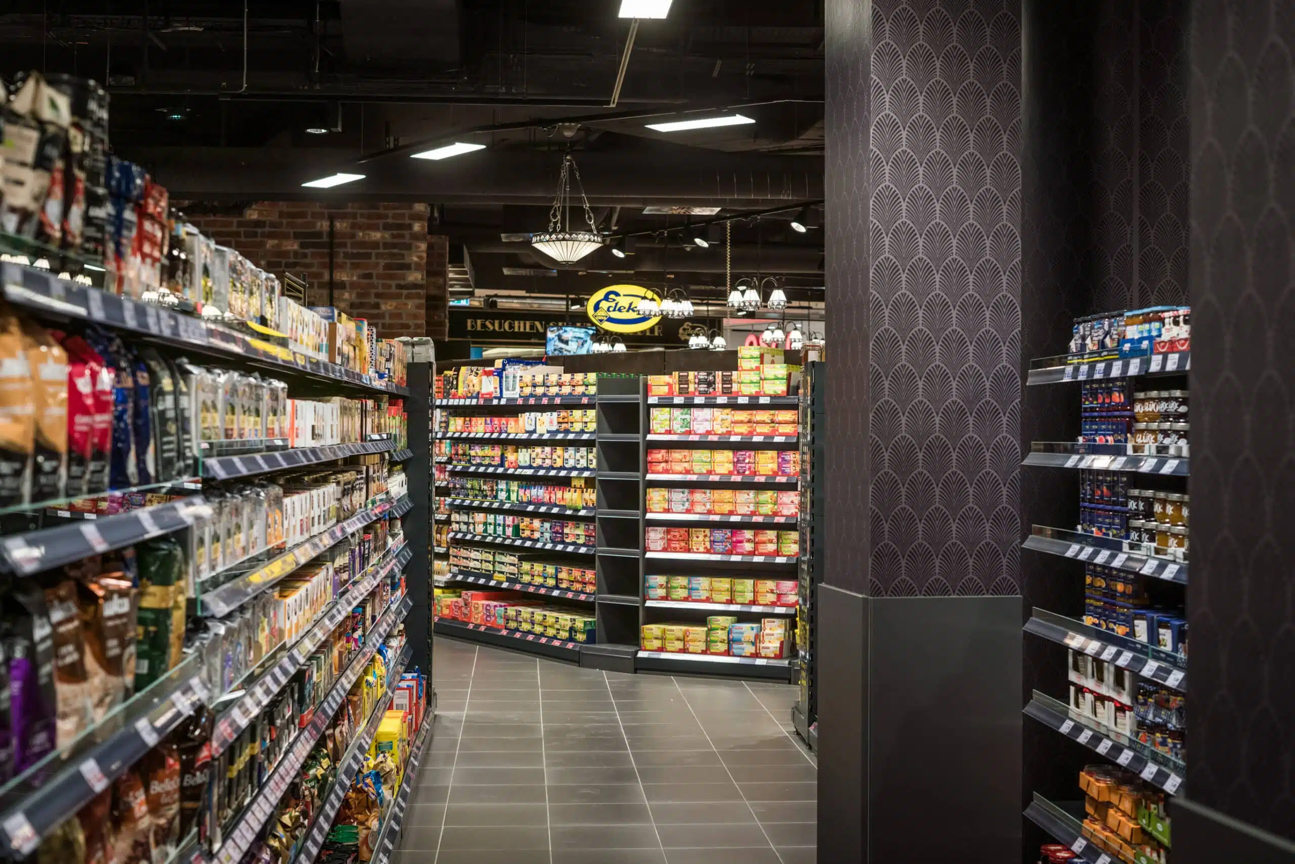 EDEKA mit nostalgischem Flair: Art-déco-Tapeten, stilvolle Beleuchtung und eine elegante Warenpräsentation schaffen ein einzigartiges Einkaufserlebnis. Hier trifft Tradition auf Moderne – für ein unvergleichliches Shopping-Erlebnis in edlem Ambiente.