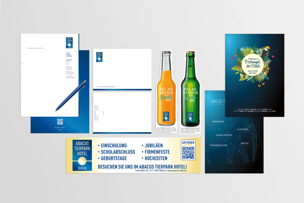 Eine Sammlung verschiedener Werbematerialien für das Abacus Tierpark Hotel. Enthalten sind Briefpapier, Visitenkarten, Banner, Getränkewerbung und Broschüren mit Natur- und Tiermotiven sowie einem modernen Design in Blau- und Grüntönen.