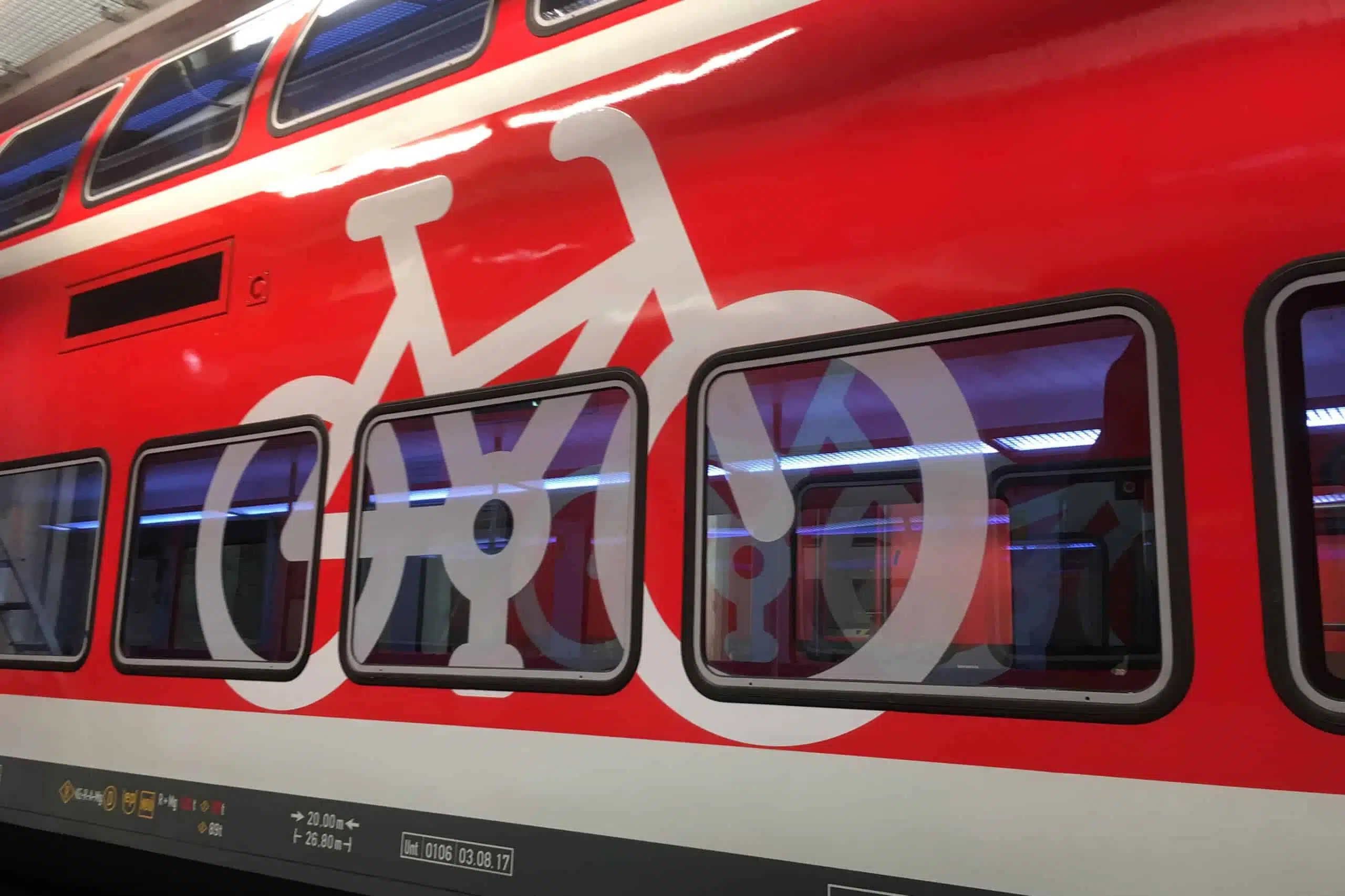 Das Bild zeigt einen rot-weißen Zug mit einem großen weißen Fahrradsymbol auf der Außenverkleidung. Das Design erstreckt sich über Fenster und Karosserie, wodurch ein einheitliches Bild entsteht.