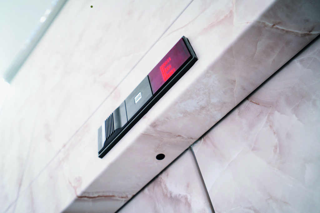Nahaufnahme einer modernen Aufzugsanzeige in einem Gebäude mit einer hochwertigen Marmoroptik-Wand. Die digitale Anzeige leuchtet rot und zeigt die aktuelle Etage an. Die Wandverkleidung hat eine realistische Marmormaserung mit dezenten, natürlichen Farbverläufen, die für ein edles Ambiente sorgen.