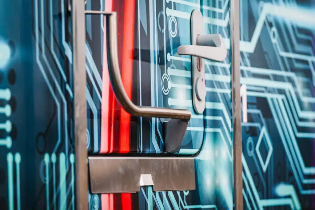 Nahaufnahme der Tür einer Lokomotive mit einem digitalen Schaltkreis-Design in Blau und roten Lichtakzenten. Deutlich zu sehen sind ein stabiler Metallhandlauf, eine silberne Türklinke mit Schloss und eine Einstiegsstufe aus Metall. Die glänzende Oberfläche der Folierung reflektiert das Umgebungslicht und verstärkt den modernen, technologischen Look.